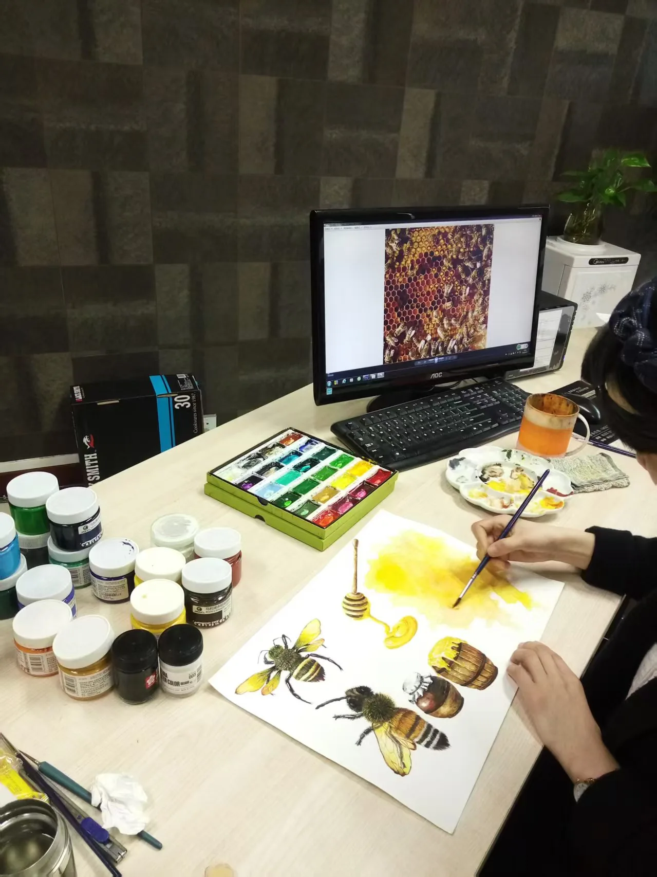 Designer desk with watercolor palette and artwork in progress